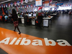 An employee walks past a logo of Alibaba Group at its headquarters on the outskirts of Hangzhou, Zhejiang province, in this May 17, 2010 file photo. REUTERS/Stringer/Files