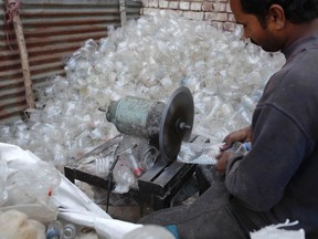 A laborer cuts the edges of bottles to prepare them for shredding at a plastic recycling factory in Lahore.

REUTERS/Mohsin Raza