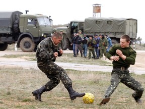 Ukrainian servicemen play with a football near Russian military vehicles at the Belbek Sevastopol International Airport in the Crimea region March 4, 2014. (REUTERS)