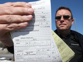 Const. Pete Dawson shows off his mitt full of $280 distracted driving tickets on Tuesday, March 18, 2014. All the tickets were issued within an hour on the first day of doubled fines for driving while talking on a cellphone. 
(DOUG HEMPSTEAD/OTTAWA SUN)