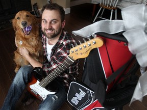 Ryan DeLong and his dog "Wilfred" sit wit a guitar and golf bag that he traded for in Winnipeg, Man. Tuesday March 18, 2014 as part of a charitable event called Bigger and Better for Animals. (Brian Donogh/Winnipeg Sun)