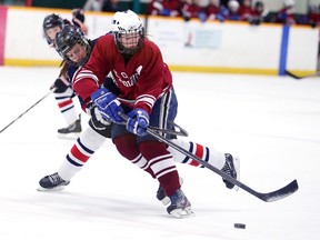 Brittany Reinhardt of the St. Charles Cardinals fights for the puck with an unidentified Louis-Riel player during OFSAA  qaureter-final action from the Gerry McCrory Countryside Sports Complex on Wednesday night.