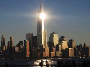 The sun reflects off New York's One World Trade Center as people stand in a park in Hoboken, New Jersey in this file photo from September 29, 2013. (REUTERS/Gary Hershorn/Files)