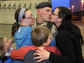 Maj. Ian McGregor kisses his wife Kate while caught in a group hug from children Alicia, 8, and Josephine, 15, and Eric, 10, at the Edmonton Garrison Tuesday. McGregor was among the last of Canada?s troops to return home from Afghanistan last week. (Dan Riedlhuber/Reuters)