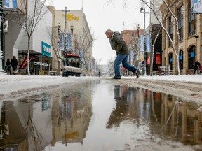 A pedestrian scoots across a wet Stephen Avenue in downtown Calgary, Alta., on Thursday March 20, 2014. Quickly melting snow fell throughout the day, creating slushy and slippery conditions on why was the first day of spring. (Lyle Aspinall/QMI Agency)