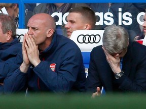 Arsenal manager Arsene Wenger (right) and coach Steve Bould react during their English Premier League loss to Chelsea at Stamford Bridge in London March 22, 2014. (REUTERS/Eddie Keogh)