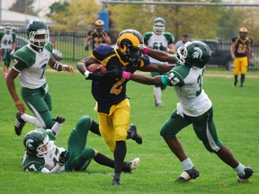 St. Joseph’s Catholic High School star Esaie Mboko stiff-arms a defender from Mother Teresa Catholic Secondary School during a 36-23 St. Joe’s win in October, 2013.