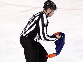 Linesmen Scott Cherrey picks up an Edmonton Oilers sweater thrown on the ice following a third period Calgary Flames goal during third period NHL action at Rexall Place, in Edmonton Alta., on Saturday March 22, 2014. David Bloom/Edmonton Sun/QMI Agency