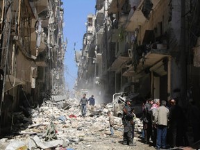 Free Syrian Army fighters and civilians inspect a site hit by, what activists said was, an airstrike by forces loyal to Syria's President Bashar al-Assad in Aleppo's district of al-Sukari March 23, 2014. REUTERS/Hosam Katan