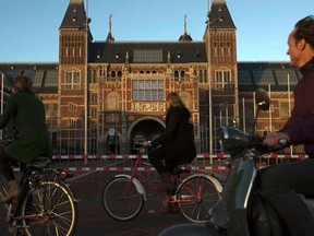People cycle past the closed Rijksmuseum at the Museumplein in Amsterdam March 23, 2014. U.S. President Barack Obama, who will be attending the Nuclear Security Summit in the Hague which is held from March 24 to 25, will visit the Rijksmuseum on Monday. REUTERS/Cris Toala Olivares