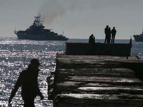 People watch Russian ships blockading the exit of Donuzlav bay in Crimea, where three Ukrainian navy ships have refused to surrender to Russian forces March 23, 2014. REUTERS/Baz Ratner