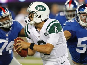 New York Jets quarterback Mark Sanchez scrambles away from New York Giants Johnathan Hankins (L) and Aaron Curry (R) on a play Sanchez injured his shoulder in the fourth quarter of their NFL preseason football game in East Rutherford, New Jersey, August 24, 2013. (REUTERS)