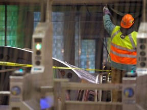 A worker puts up a tarp to cover the scene where a Chicago Transit Authority subway train crashed into a platform at O'Hare International Airport in Chicago March 24, 2014. Thirty-two people were injured after the train derailed and hit a platform early on Monday, with its front car landing on an escalator and stairs, a city fire official said.  REUTERS/Jim Young