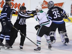Dallas Stars forward Antoine Roussel is restrained by linesman Lonnie Cameron as Winnipeg Jets defenceman Keaton Ellerby (left) and goaltender Al Montoya look on after the end of their NHL game at MTS Centre in Winnipeg, Man., on Sun., March 16, 2014. (Kevin King/Winnipeg Sun/QMI Agency)