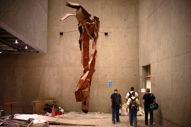 Construction workers walk past steel facade segments, also known as "Impact Steel", that were torn apart when hijacked United Flight 175 tore into the South Tower of the World Trade Center on September 11, 2001, as it hangs inside a center passage area of the 911 Memorial Museum, which is under construction, at the World Trade Center site in New York, July 2, 2013. The Museum is scheduled to be opened to the public in the Spring of 2014.   REUTERS/Mike Segar    (UNITED STATES - Tags: DISASTER BUSINESS CONSTRUCTION)