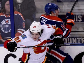 Oilers forward Jordan Eberle is taken into the boards by Flames player Kenny Agostino during Saturday's game at Rexall Place. (David Bloom, Edmonton Sun)