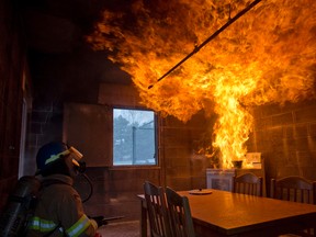 Firefighter Mark Hancock stands by with a fire extinguisher as a column of fire shoots out of a pot of oil on a stovetop after water was added during an exercise at the London Fire Department Training Division on Wellington Road in London, Ontario on Tuesday March 25, 2014. (CRAIG GLOVER, The London Free Press)