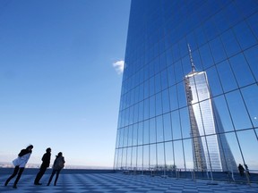 People on a press tour look up at a reflection of the One World Trade Center tower from a terrace on the 57th floor of the soon to be opened 4 World Trade Center tower in New York, November 8, 2013. (REUTERS/Mike Segar)