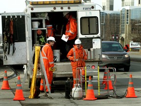 EPCOR employees stand near a sewer hole in downtown Edmonton on Tuesday after an underground ‘flash and bang’ left a worker shaken up. (PERRY MAH/Edmonton Sun)