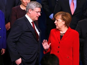 Canada's Prime Minister Stephen Harper, left, and Germany's Chancellor Angela Merkel, right, talk as they take part in a family picture with other world leaders during the Nuclear Security Summit in The Hague March 25, 2014. (REUTERS/Yves Herman)