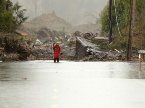 A rescuer stands on a flooded Highway 530 as search work continues in the mud and debris from a massive mudslide that struck Oso near Darrington, Washington March 27, 2014. (REUTERS/Ted S. Warren/Pool)
