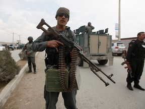 Afghan policemen stand near an election commission office during an attack by gunmen in Kabul March 29, 2014. Taliban insurgents attacked the Independent Election Commission headquarters in the Afghan capital of Kabul on Saturday, staff and police said, the latest in a spate of attacks ahead of next week's presidential election. REUTERS/Mohammad Ismail