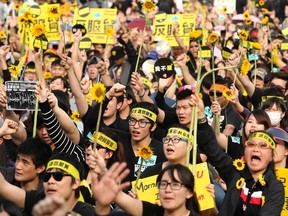 Demonstrators holding sunflowers shout slogans in front of the Presidential Office in Taipei March 30, 2014. Thousands of demonstrators marched the streets on Sunday to protest against the controversial trade pact with mainland China. The Chinese characters on the head bands read, "Reject the trade pact." REUTERS/Toby Chang