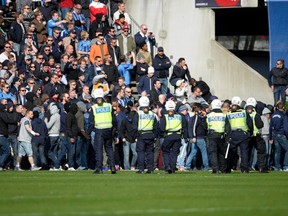 Police officers try to control supporters of Stockholm club Djurgarden who stormed the pitch during their Swedish league soccer match between Helsingborgs and Djurgarden, at Olympia stadium in Helsingborg March 30, 2014. A Djurgarden supporter has died from head injuries sustained in an assault before his team's opening Swedish league match at Helsingborg, police said on Sunday. (REUTERS)
