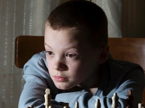 Justin Hack, 11, sits at home with the first-place trophy he won in the city-wide Grade 6 chess tournament. (DEREK RUTTAN, The London Free Press)