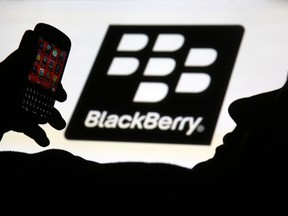 A man is silhouetted against a video screen with the Blackberry logo as he pose with a Blackberry Q10 in this photo illustration taken in the central Bosnian town of Zenica, Sept. 21, 2013.  REUTERS/Dado Ruvic