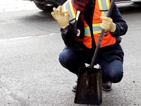 Mayor Don Iveson poses for a photo beside the pothole he helped fill along 98 Avenue near 97 Street, in Edmonton, Alta., on Friday Feb. 21, 2014. David Bloom/Edmonton Sun