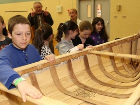Ethan McAvoy-Flesher, 11, left, examines a birch bark canoe during a workshop for students at Ecole Notre-Dame de la Merci in Coniston, ON. on Monday, March 31, 2014. Marcel Labelle, of Metis heritage, conducted the workshop and explained the importance of  the canoe for Metis and First Nations communities to students during the presentation, which included  the steps and material used to build a birch bark canoe. During the workshop, students also learned to build a miniature birch bark canoe.JOHN LAPPA/THE SUDBURY STAR/QMI AGENCY