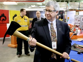 Minister of Environment and Sustainable Resource Development Robin Campbell looks at a tool used to fight wildfires called a Pulaski, following a press conference about the upcoming wildfire season, in Edmonton Alta., on Tuesday April 1, 2014. David Bloom/Edmonton Sun