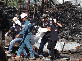 Rescue workers walk amongst debris as they carry a body away from the scene of an explosion at a metal recycling shop in Bangkok on April 2, 2014. (REUTERS/Stringer)
