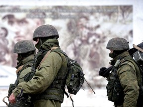 Russian soldiers walk past a recruitment poster for the Ukrainian armed forces while patrolling the area surrounding the Ukrainian military unit in Perevalnoye, outside Simferopol, on March 20, 2014. Kiev will never recognize Russia's annexation of Crimea and will fight for the "liberation" of the strategic Black Sea peninsula, Ukraine's parliament said in a resolution adopted on March 20.