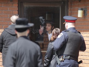 An unidentified member of Lev Tahor gestures to Chatham-Kent Children's Services workers through a locked door to the ultra-orthodox community's classrooms while a number of children remained indoors. (Vicki Gough/QMI AGENCY)