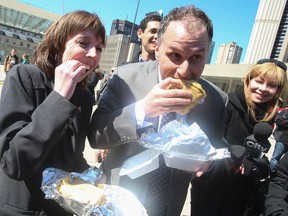 Councillors Mary-Margaret McMahon, left, and Josh Colle enjoy some hot roti from Randy's Roti truck at a lunch break on Wednesday. Toronto city council debated new food truck rules on Wednesday. (JACK BOLAND/Toronto Sun)
