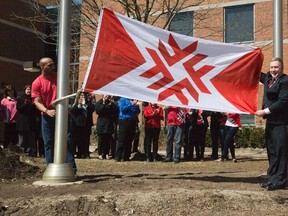 Fanshawe College president Peter Devlin (right) shows off the school's new logo during a flag raising ceremony in London, Ont. on Wednesday April 2, 2014.DEREK RUTTAN/The London Free Press/QMI Agency