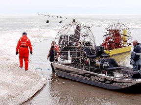 A yellow airboat that struck a submerged log Thursday morning on the ice-covered surface of Mitchell's Bay, tossing its three occupants into four feet of frigid water, is hauled back to shore following rescue efforts. The trio managed to climb on top of the overturned boat and wait for help to arrive. (BOB BOUGHNER/ THE CHATHAM DAILY NEWS/ QMI AGENCY)