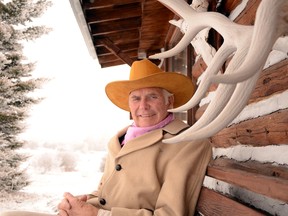 Don Brestler sits outside of his hand-built log cabin.