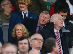 Manchester United's former manager Alex Ferguson (C) looks on ahead of their English Premier League soccer match against Aston Villa at Old Trafford in Manchester, northern England March 29, 2014. (REUTERS/Phil Noble)