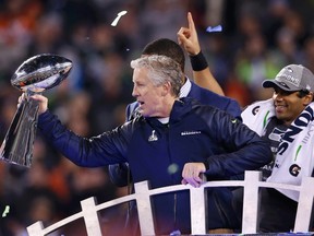 Seattle Seahawks head coach Pete Carroll holds up the Vince Lombardi Trophy next to quarterback Russell Wilson (R) after they defeated the Denver Broncos 
in the NFL Super Bowl XLVIII football game in East Rutherford, New Jersey, February 2, 2014. (REUTERS/Shannon Stapleton)