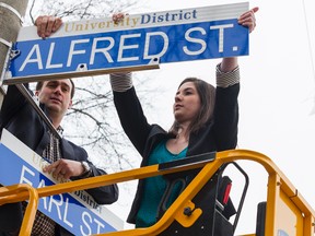Mayor Mark Gerretsen and Catherine Wright, municipal affairs commissioner of the Alma Mater Society at Queen’s University, install the first of 112 new street signs that distinguish the "University District" at Alfred Street and Earl Street on Friday afternoon. 
BRIANNE STE MARIE LACROIX/KINGSTONWHIG_STANDARD/QMIAGENCY