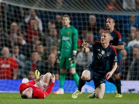 Bayern Munich's Bastian Schweinsteiger gestures to Manchester United's Wayne Rooney (L) after fouling him during their Champions League quarter-final first leg soccer match at Old Trafford in Manchester, April 1, 2014. (REUTERS/Stefan Wermuth)