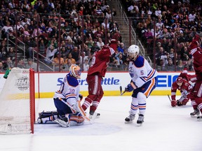 Apr 4, 2014; Glendale, AZ, USA; Phoenix Coyotes defenseman Oliver Ekman-Larsson (23) scores a power play goal on Edmonton Oilers goalie Ben Scrivens  (30) while falling to the ice as defenseman Mark Fraser (5) defends and right wing Shane Doan (19) celebrates during the second period at Jobing.com Arena. Mandatory Credit: Matt Kartozian-USA TODAY Sports