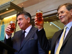 Ontario Finance Minister Charles Sousa — seen here raising a pint with LCBO president Bob Peter, right — at April 1, 2014 announcement that 'LCBO Express' stores would be opening inside select Ontario grocery stores. (Dave Abel/Toronto Sun)