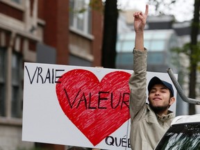 A demonstrator protests near a sign saying "True value Quebec" as they marched against Quebec's proposed Charter of Values in Montreal, September 14, 2013. Thousands took to the streets to denounce the province's proposed bill to ban the wearing of any overt religious garb by government paid employees. REUTERS/ Christinne Muschi