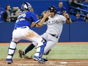Toronto Blue Jays catcher Josh Thole prepares to tag out New York Yankees catcher Francisco Cervelli at the Rogers Centre in Toronto, April 5, 2014. (TOM SZCZERBOWSKI/Getty Images/AFP)