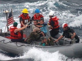 Sailors from Oliver Hazard Perry-class frigate USS Vandegrift assist in the rescue of a family with a sick infant via the ship's small boat as part of a joint U.S. Navy, Coast Guard and California Air National Guard rescue effort as seen in this U.S. Navy handout photo taken in the Pacific Ocean on April 6, 2014. (REUTERS/U.S. Navy Photo/Handout via Reuters)