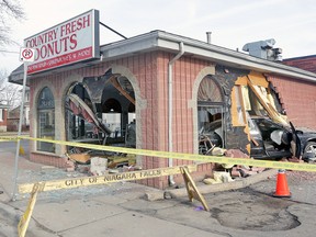 A car crashed through the front window of Country Fresh Donuts in Niagara Falls, Ont., shortly after 2 a.m. on Monday. Co-owner Loc Thong and her daughter Darlene look over the damage. (MIKE DIBATTISTA/QMI Agency)